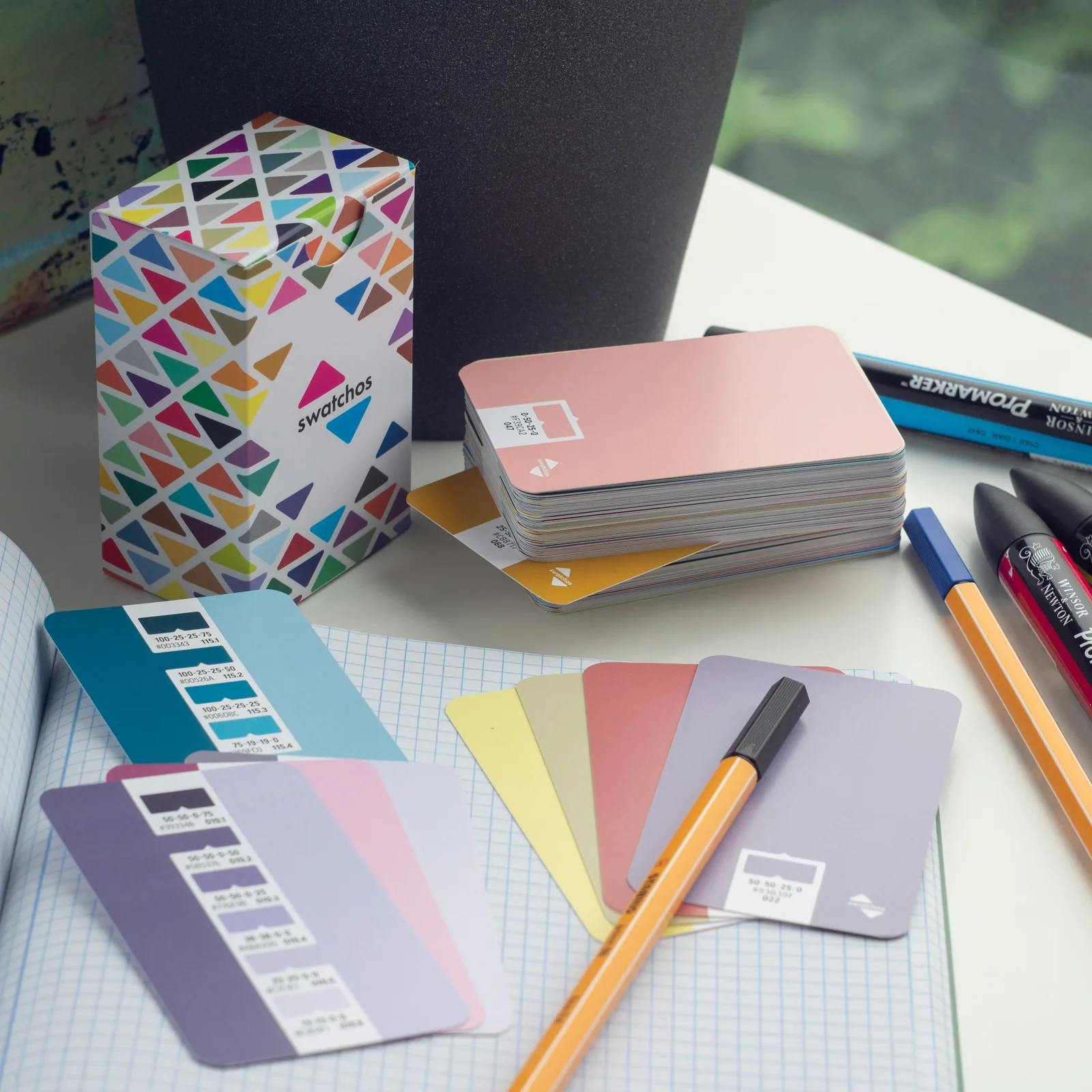 A desk with color swatches, pens, and a notebook.