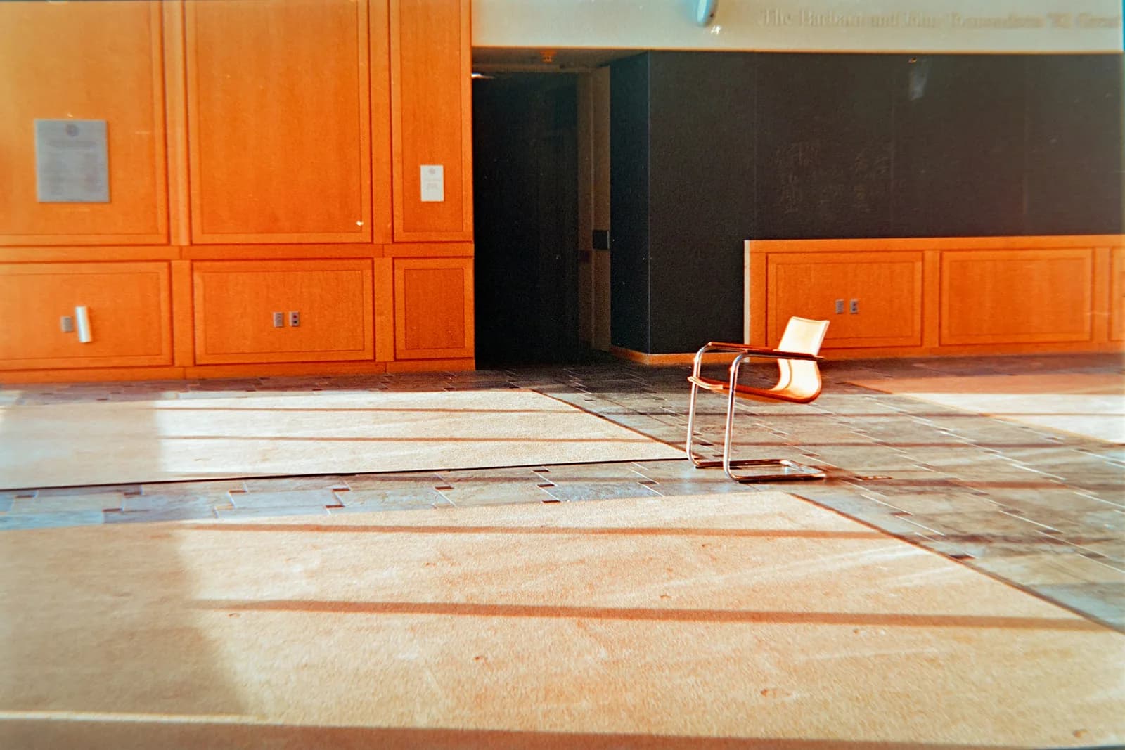A single empty chair in a quiet room with warm wooden walls.