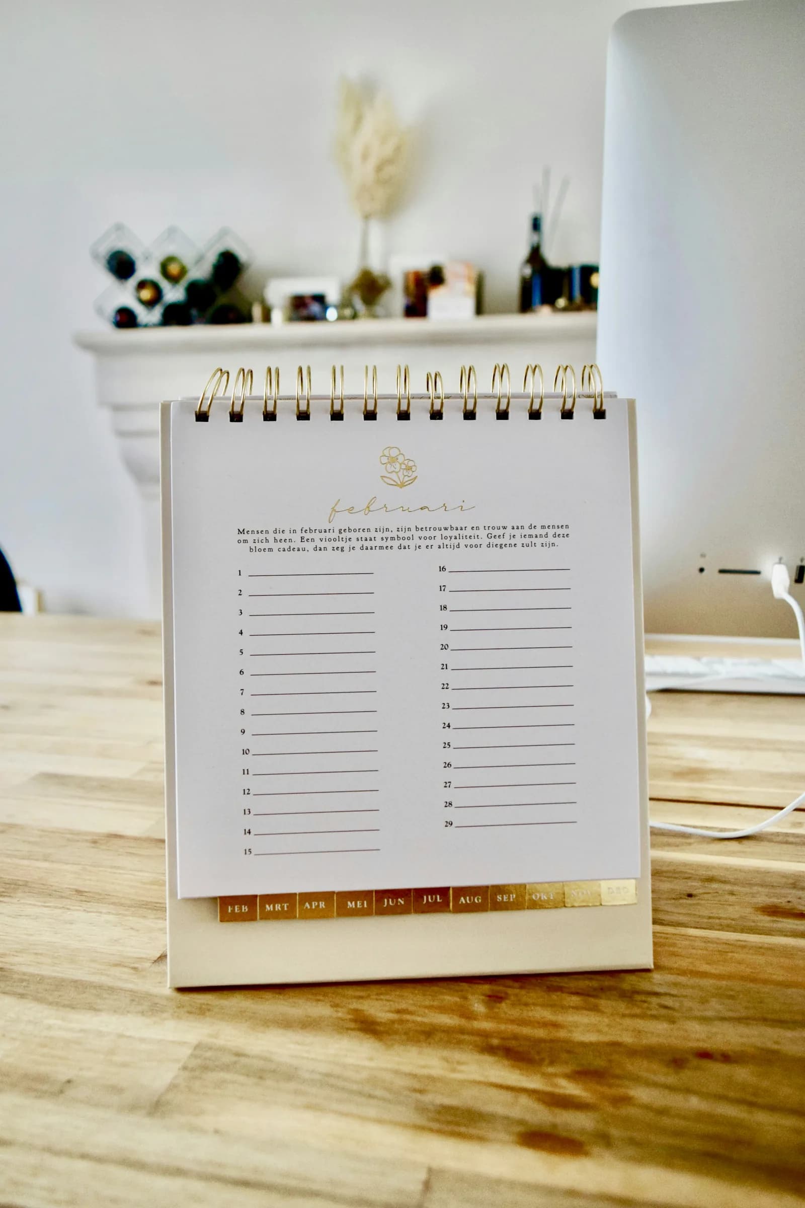 A paper calendar open to a week, lying on a wooden table.